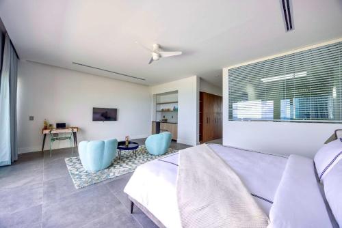 a bedroom with a bed and two blue chairs at Villa Skyline with stunning Ocean View in Turtle Cove