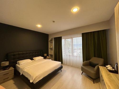 a bedroom with a bed and a chair and a window at TUNA OTEL in Gelibolu