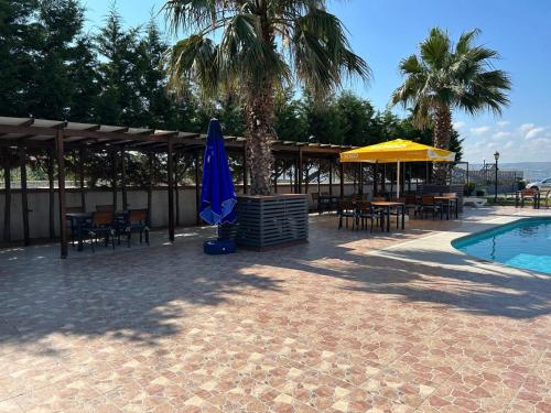 a swimming pool with a umbrella and chairs and a table and a umbrella at TUNA OTEL in Gelibolu