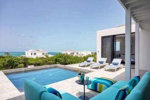 a villa with a swimming pool and blue chairs at Skyline Villas - Villa Pluto Oceanfront with Private Pool in Providenciales