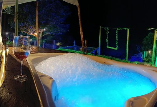a glass of wine next to a tub with a glass of wine at Domo Cachoeira São Bernardo in Piranguçu