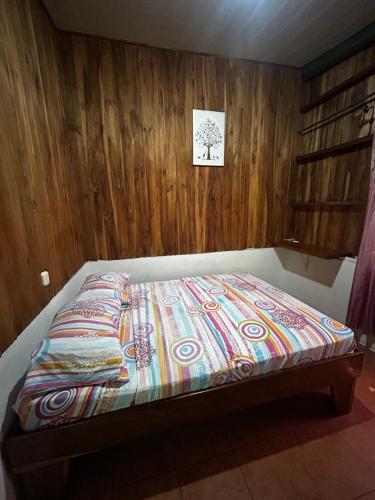 a bed in a room with a wooden wall at Ballena Oasis Homes & Glamping in Uvita