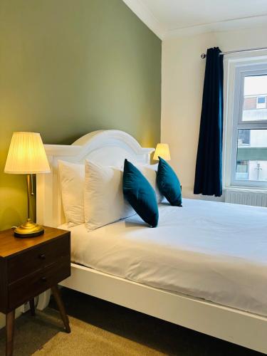 a bedroom with a bed with blue pillows and a window at The Inn at Cheltenham Parade in Harrogate