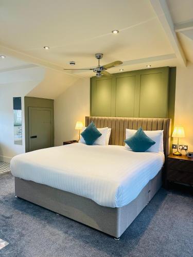 a bedroom with a large white bed with blue pillows at The Inn at Cheltenham Parade in Harrogate