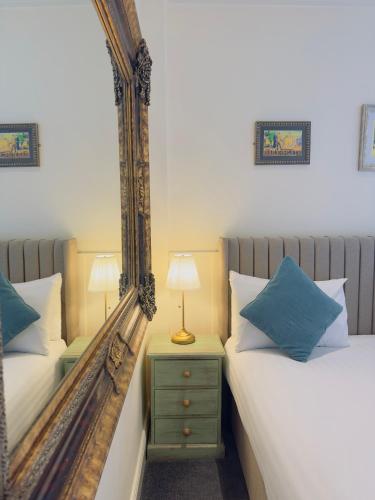 a bedroom with two beds and a mirror at The Inn at Cheltenham Parade in Harrogate