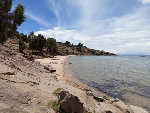 プーノにあるTiticaca Lodge Taquileの曇りの日の岩と海のあるビーチ