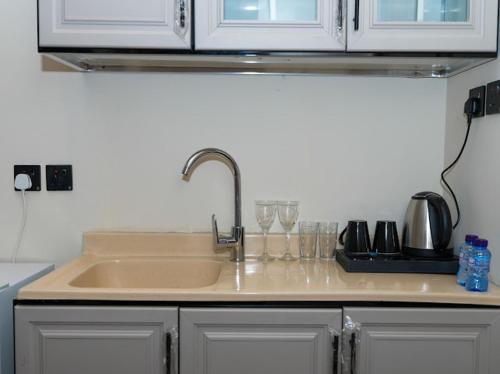 una encimera con fregadero y copas de vino en رايز العارض للشقق المخدومة, en Riad