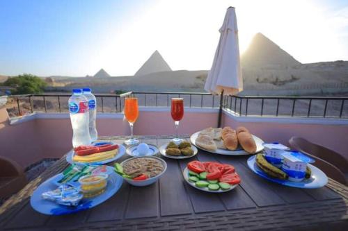 a table with plates of food and drinks on a balcony at Pyramids 3 minutes Walking &View INN in Cairo