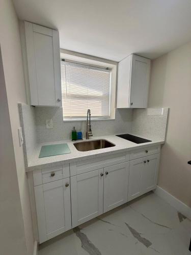 a kitchen with white cabinets and a sink at Guayabita's House in Miami