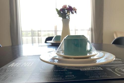 einen Teller auf einem Tisch mit einer Vase Blumen in der Unterkunft Excelente localização - com garagem in Petrolina