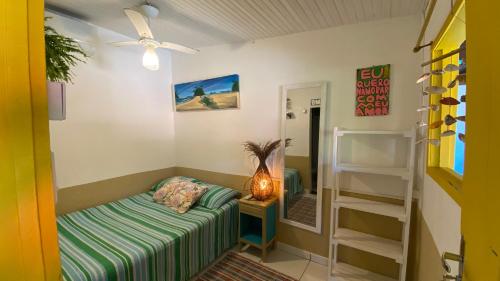 a small room with a bed and a shelf at Tia Chica Camburi in Camburi
