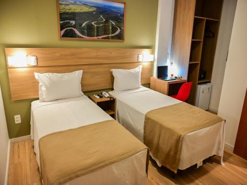 um quarto de hotel com duas camas e uma cadeira vermelha em Bristol Marambaia Belém em Belém