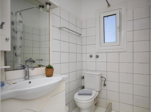 a white bathroom with a toilet and a sink at Joanna Apartments in Mikri Vigla