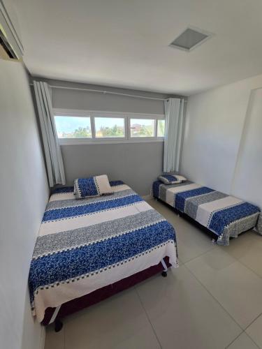 two beds in a room with a window at Refúgio da Praia Aracaju in Aracaju