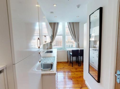 a white kitchen with a sink and a table at Heart of Notts, Modern Studio, Great City Views in Nottingham