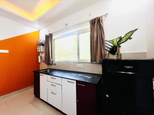 cocina con nevera negra y ventana en Elegant 4Bhk Stay With Pool Near Beaches 2BHKX2, en Vagator