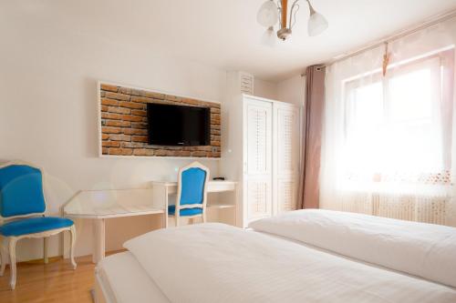 a bedroom with two beds and a desk and a tv at Der Torwirt Radstadt in Radstadt