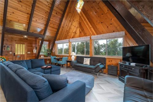 a living room with blue couches and a flat screen tv at Quail Haven- A-frame cabin with hot tub, views, and more in Oakhurst
