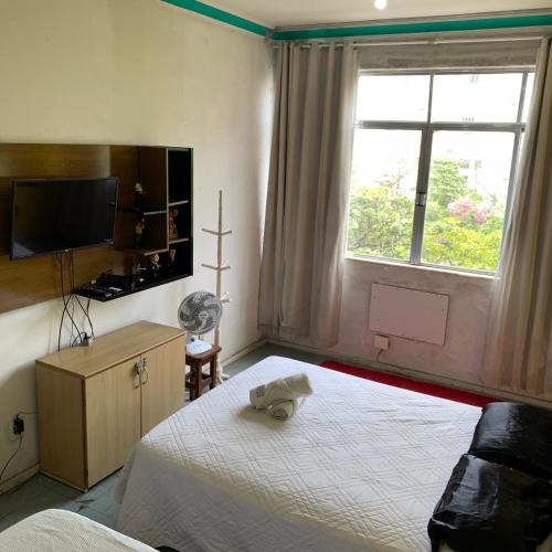a bedroom with a bed and a tv and a window at Quarto vista mar in Rio de Janeiro