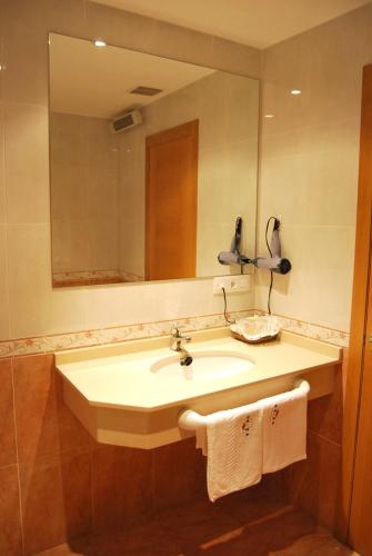a bathroom with a sink and a mirror and towels at Hotel Plaza in Portonovo