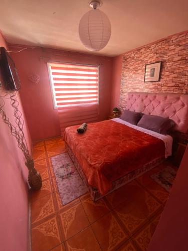 a bedroom with a bed with a red comforter at Hotel del valle in Melipilla