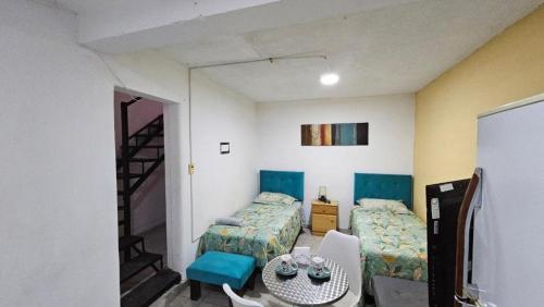 a room with two beds and a table and a staircase at Hostal Quintamar Viña del mar in Viña del Mar