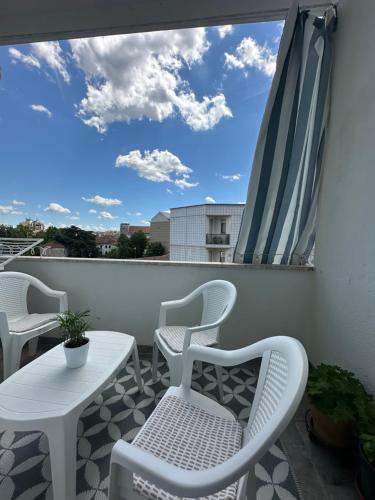a balcony with white chairs and a table and a window at Appartamento Vacanza Centro Asti in Asti