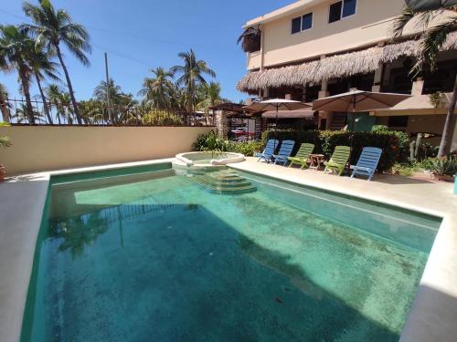 a swimming pool with two chairs and a building at Hotel Papaya Surf in Puerto Escondido