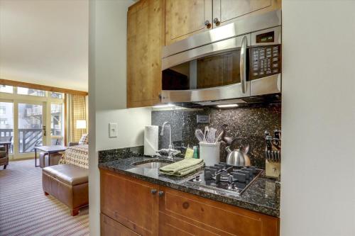 une cuisine avec un évier et un micro-ondes dans l'établissement StoweBound at The Lodge at Spruce Peak, à Stowe Mountain