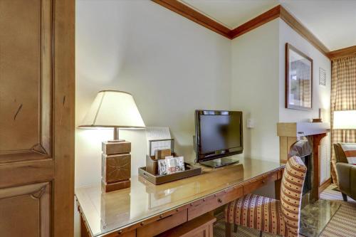 Cette chambre comprend un bureau avec une télévision et une lampe. dans l'établissement StoweBound at The Lodge at Spruce Peak, à Stowe Mountain