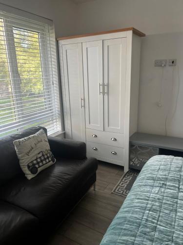 a bedroom with a couch and a bed and a cabinet at COSY Rooms in Grove Park