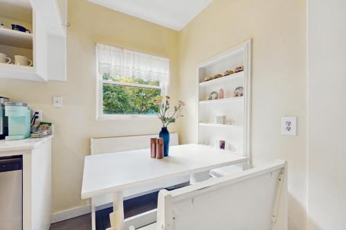 a kitchen with a white table and a window at The Garden Retreat in Mount View