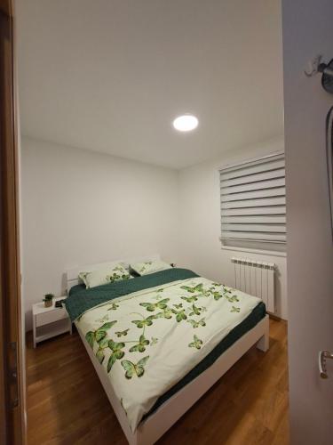 a bedroom with a bed with a green comforter at Stan na dan Ramonda in Donje Mladice
