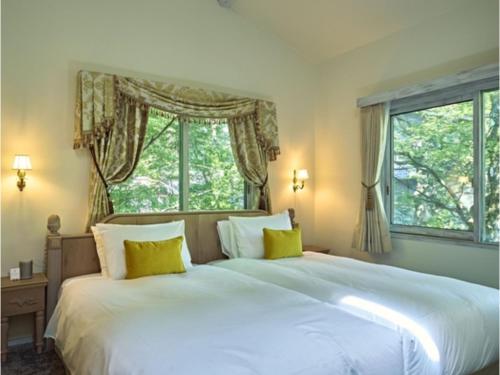 a bedroom with a large white bed with yellow pillows at Auberge de Primavera - Vacation STAY 40819v in Shin-karuisawa