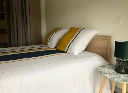 Cama con almohadas blancas y mesa con lámpara en Appartement F3 - 1er étage, en Pontorson