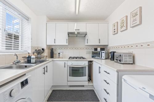 a white kitchen with white cabinets and a sink at Central Peaceful Home with Parking, Wi-Fi and Garden in Stafford