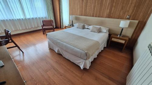 a hotel room with a bed and a chair at Hotel y Cabañas Llanuras de Diana - Caja Los Andes in Puerto Natales