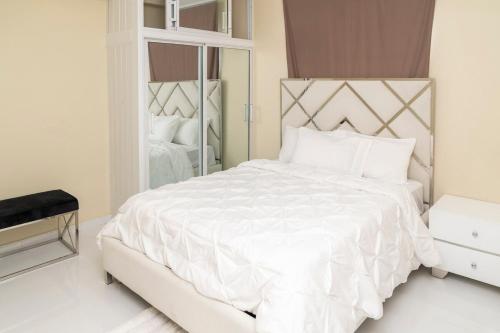 a bedroom with a white bed with a large mirror at La Isla Royal - Pool Side Suite in Miches