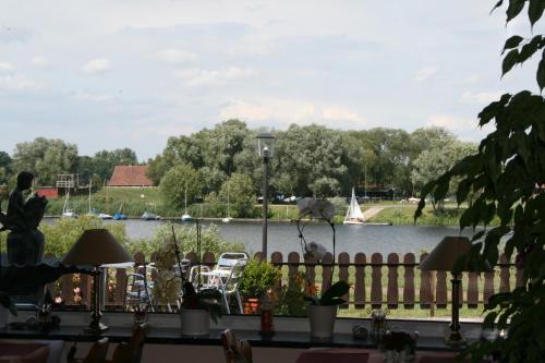 a view of a lake with a fence and a boat at Hotel Seeblick garni in Gartow
