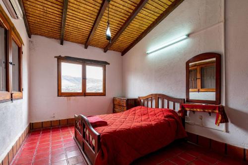 a bedroom with a red bed and a window at La Ramada in Tafí del Valle