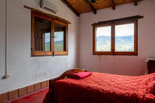 a bedroom with a red bed and two windows at La Ramada in Tafí del Valle