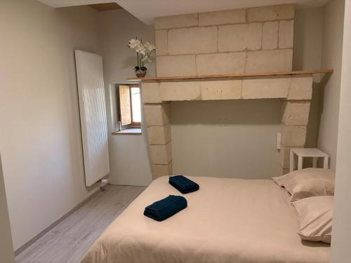 a bedroom with a bed with two blue pillows on it at Charmante maison avec piscine in Turquant