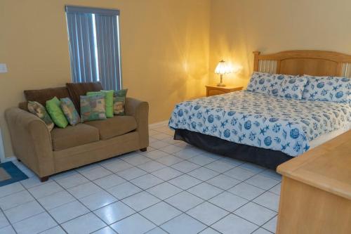 a bedroom with a bed and a couch at BBQ ok Ground Floor Duplex 1-2 block to Beach in South Padre Island