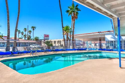 a swimming pool with blue chairs and palm trees at Historic Coronado Motor Hotel by OYO in Yuma