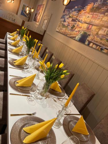 Una mesa de comedor larga con servilletas amarillas y servilletas amarillas. en Olymp Hotel, en Magdeburgo