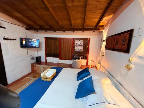 a bedroom with a large white bed with blue pillows at Cabaña & glamping para grupos de 4 a 6 personas, cerca al parque y con avistamiento de aves in Jardin