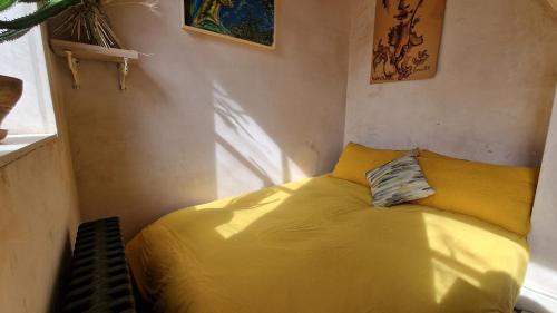 1 dormitorio con 1 cama amarilla en una habitación en Private studio New Cross patio garden, en Londres