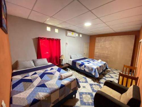 een kamer met twee bedden en een stoel erin bij Casa Cahuí in El Remate