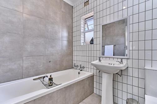 a bathroom with a bath tub and a sink and a mirror at Aviator's Nest in Kempton Park