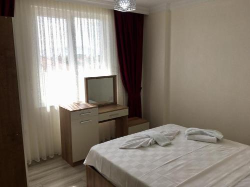 ein Schlafzimmer mit einem Bett, einem Fernseher und einem Fenster in der Unterkunft Kaya Home Ortaca Günlük Apart Daire in Ortaca